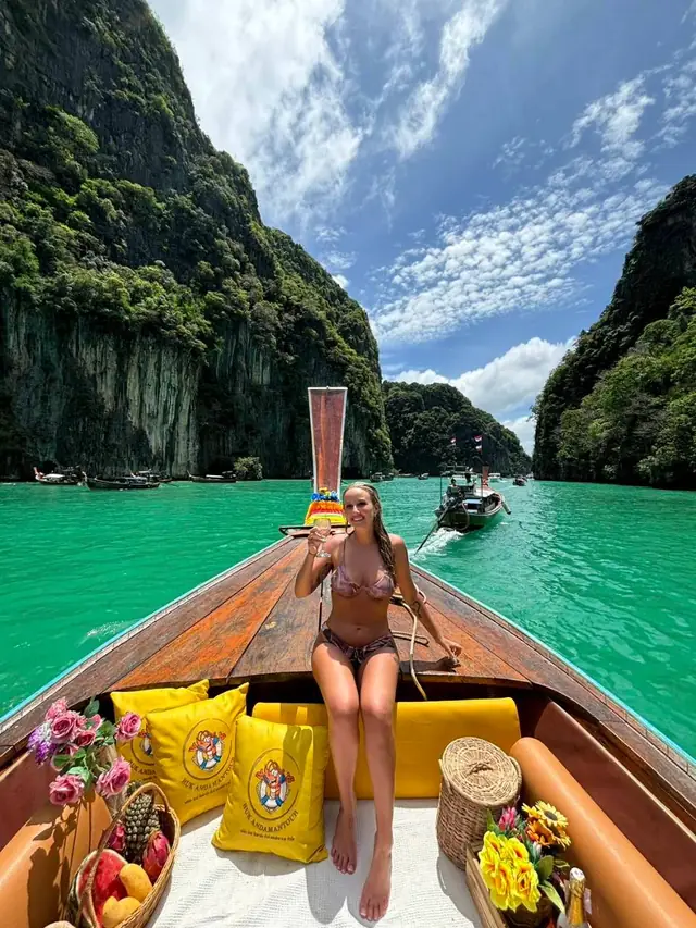 Traveller on a longtail bow past limestone cliffs
