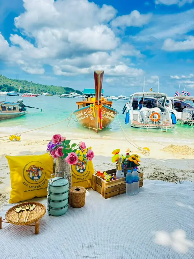 Beach picnic with a luxury longtail and speedboats behind
