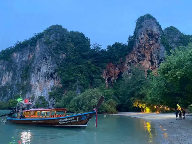 Longtail moored under limestone cliffs at dusk