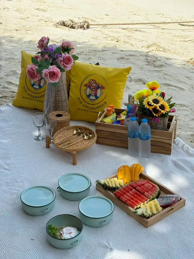 Beach picnic set with fruit, flowers and food tins