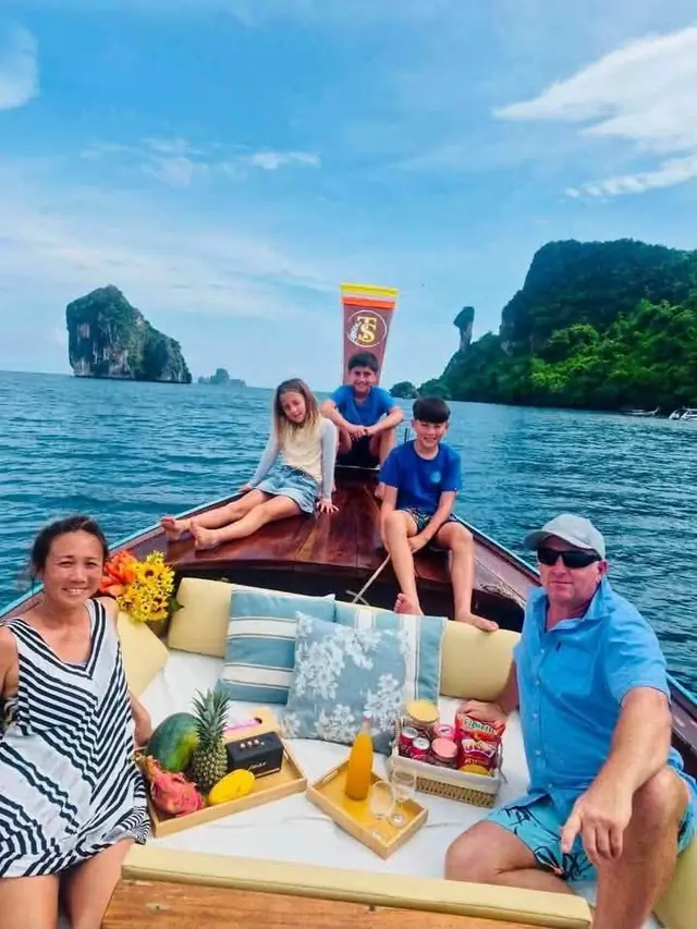 Family on a luxury longtail with a rock island behind