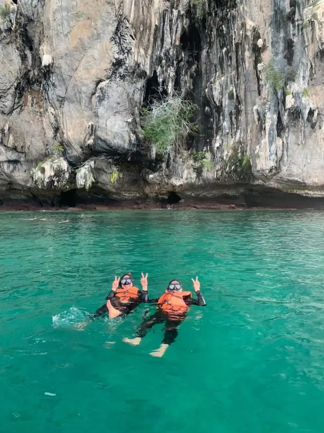 Snorkelling under a limestone cliff in clear green water