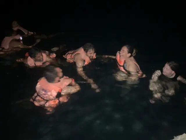 Swimming in life jackets with glowing plankton at night