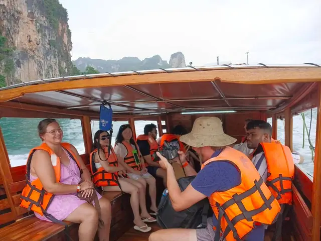 นักท่องเที่ยวในเรือหางยาว มองเห็นหน้าผาด้านหลัง